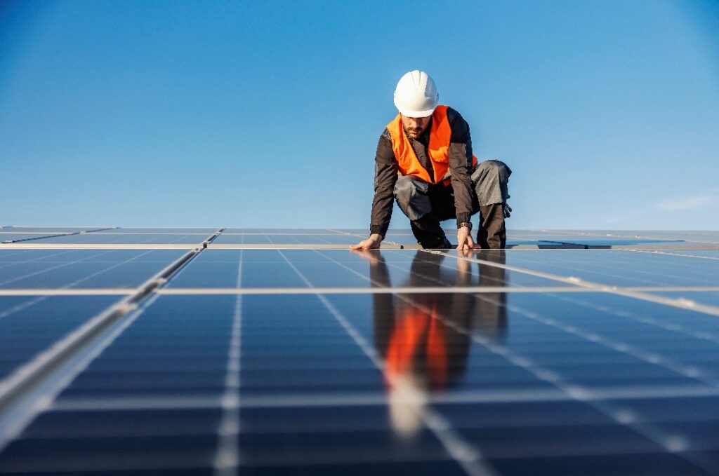 Ein Handwerker bei der Installation von Solarzellen auf dem Dach.